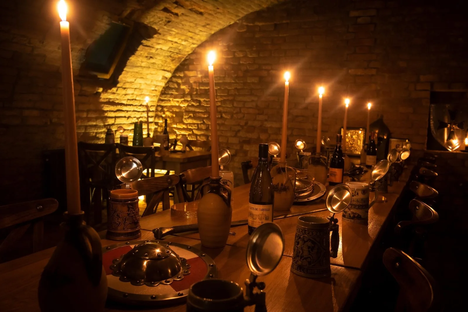Dlouhý dřevěný stůl s korbely a svícemi v Královské krčmě